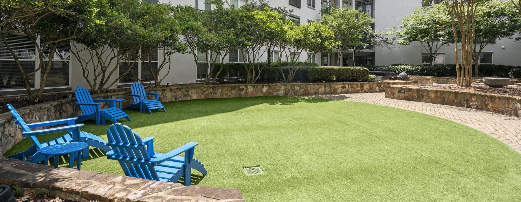 a lawn with chairs and trees in front of a building